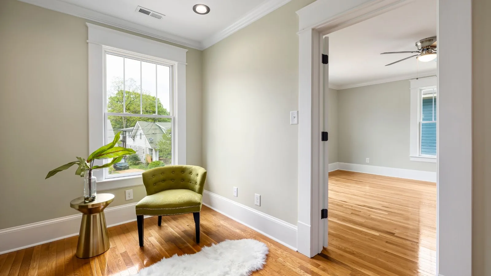 Clean bedroom and adjacent hallway with hardwood floors